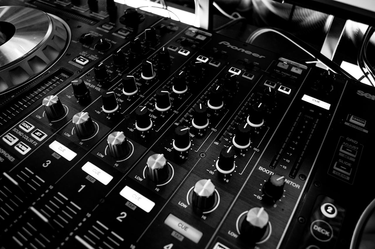 Home Black and white close-up of a DJs audio mixing console with knobs and controls.